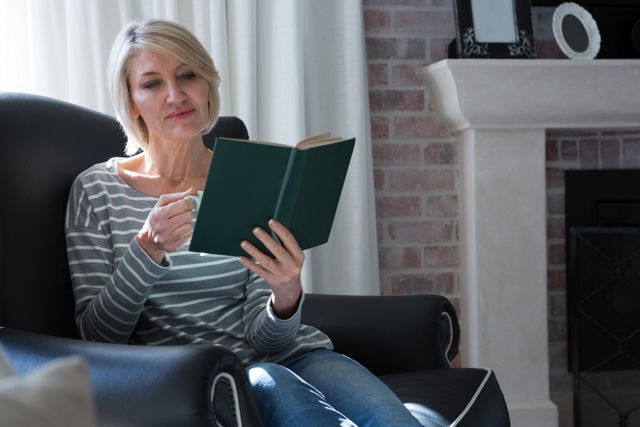 Beautiful woman reading book while having coffee in living room