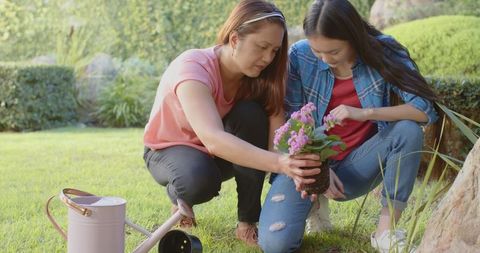 Asian Mother and Daughter Planting Flowers Together in Garden