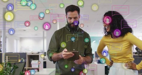 Colleagues collaborating on tablet with colorful chat icons in modern open office