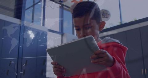 Young student holding tablet studying content in modern classroom with world map overlay