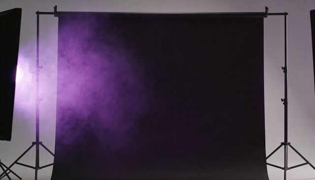 Hanging black studio backdrop with tripod stands and purple haze for moody portraits