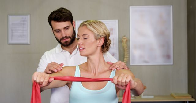 Physiotherapist assisting a woman in a healthcare clinic while she uses a resistance band for her exercise. Could be used for promotional materials for physiotherapy clinics, healthcare services, or fitness rehabilitation centers.