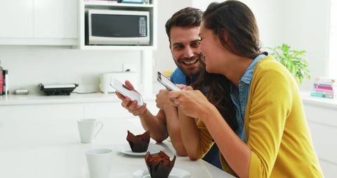 Couple Enjoying Smartphones in Modern Kitchen