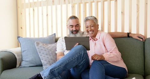 Happy Senior Couple Enjoying Time with Tablet on Cozy Couch