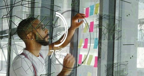 Creative planner arranging colorful sticky notes on glass with futuristic hud overlay