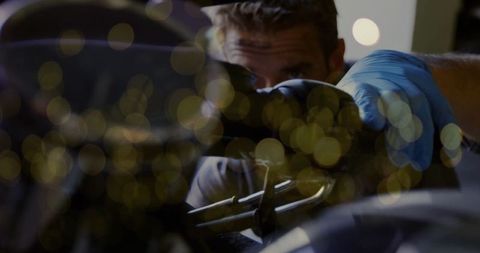 Mechanic inspecting motorcycle engine in workshop with blue gloves