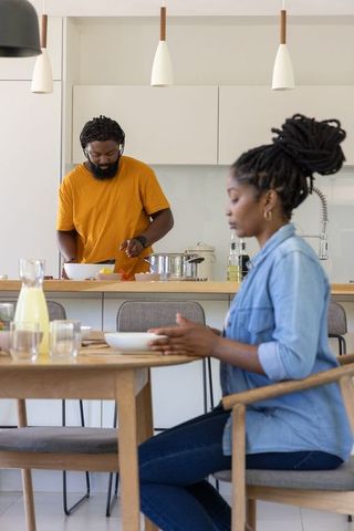 African couple preparing meal together in modern minimalist kitchen with dining table
