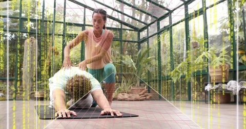 Yoga instructor guiding student through stretch in sunlit greenhouse with digital grid overlay
