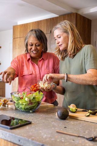 Senior Friends Enjoying Salad Preparation Together at Home Kitchen