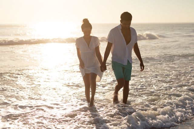 Romantic couple walking together hand in hand on the beach