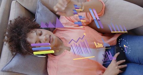 Young woman relaxing with headphones and ar data overlays on gray sofa