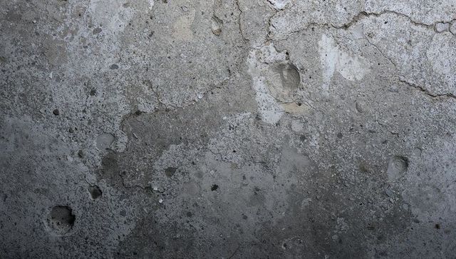 Weathered concrete wall texture with cracks, holes and stains for industrial background