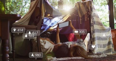 Mother and Daughter in Cozy Fort Engaging with Social Media