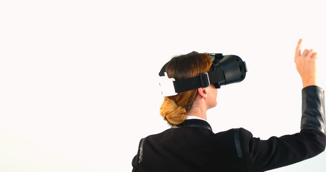 Businesswoman using virtual reality headset, pointing and interacting with virtual elements. This scene captures modern technology in business, ideal for illustrating cybersecurity, innovation, and immersive experiences in corporate environments. Suitable for articles about advanced training techniques, latest tech developments, and future workplaces.