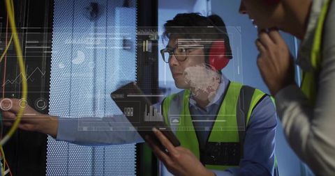 Data center technician troubleshooting server rack with tablet and headset wearing hi-vis vest