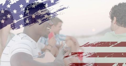 Playing acoustic guitar on sunset beach with american flag brush overlay and friends