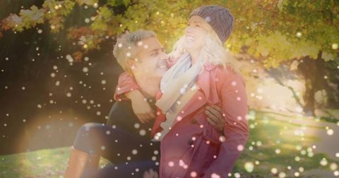 Couple laughing and embracing in autumn park with warm bokeh light and cozy knit beanie