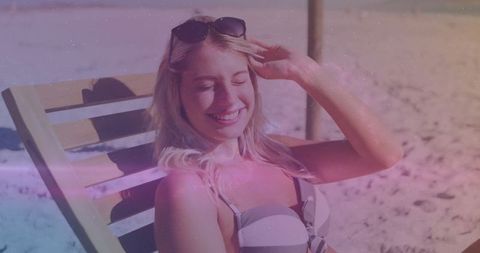 Smiling woman on beach lounge relaxing under sunlight