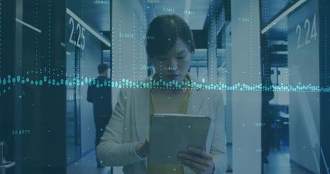 Businesswoman analyzing data on tablet in corporate hallway