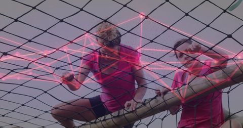Women climbing cargo net with neon data overlay demonstrating teamwork and grit