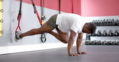 Athletic Man Performing TRX Plank in Modern Gym Setting