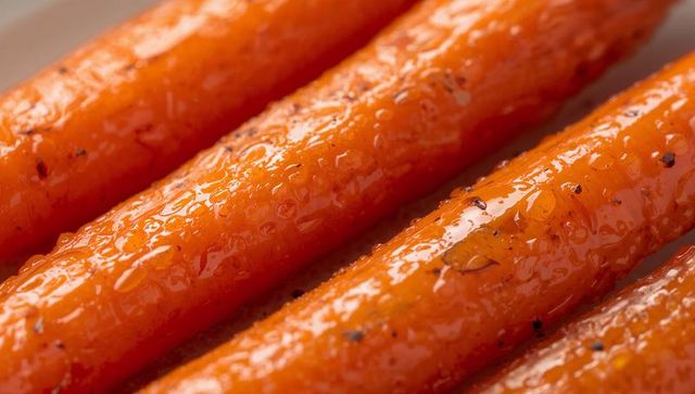 Glazed roasted carrots close-up showing caramelized texture and glossy herb pepper finish