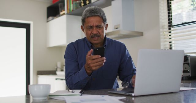 Senior Man Reading Smartphone in Modern Kitchen with Laptop - Download Free Stock Images Pikwizard.com