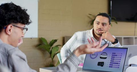 Multicultural team discussing product dashboard on laptop in casual office nook