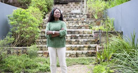 African American Woman Standing in Lush Backyard Garden by Stone Terraced Steps, Confident
