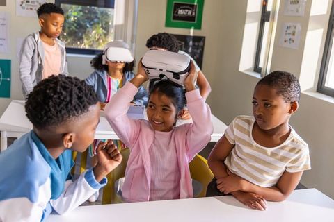 Elementary students exploring virtual reality together while girl donning vr headset