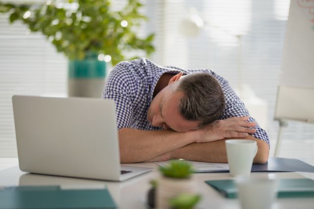 Tired executive sleeping at desk in office