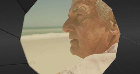Elderly man gazing at ocean horizon through angular frame