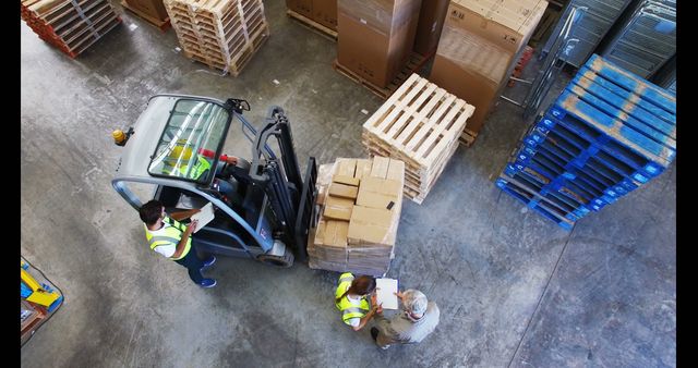 Indoor warehouse environment. Three workers managing inventory. Man in forklift moving boxes on pallets while others assist. Could be used for topics on logistics, supply chain management, warehouse operations, industrial safety, teamwork, and occupational roles.