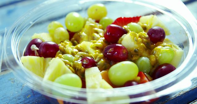 A bowl of fresh fruit salad is displayed, featuring a mix of grapes, strawberries, bananas, and passion fruit. The vibrant colors and juicy textures invite a healthy and refreshing snack option.