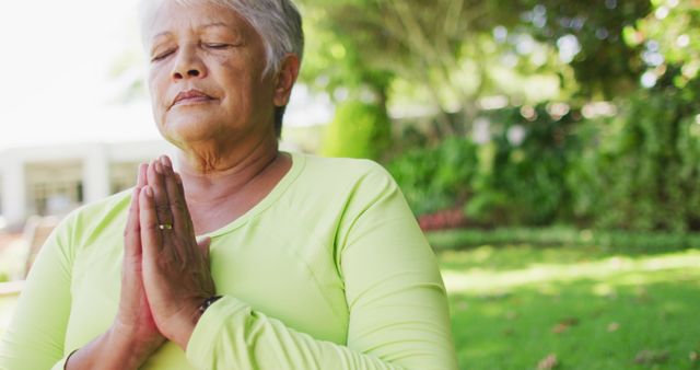 Image of relaxed biracial senior woman practicing yoga in garden. active retirement lifestyle and exercising concept.