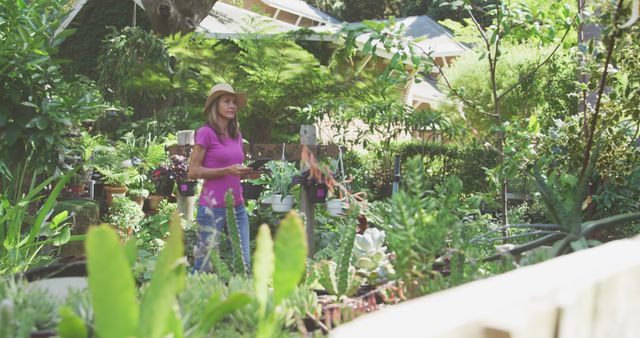Happy caucasian woman wearing hat and using tablet in sunny garden. Nature, gardening, communication and hobbies.