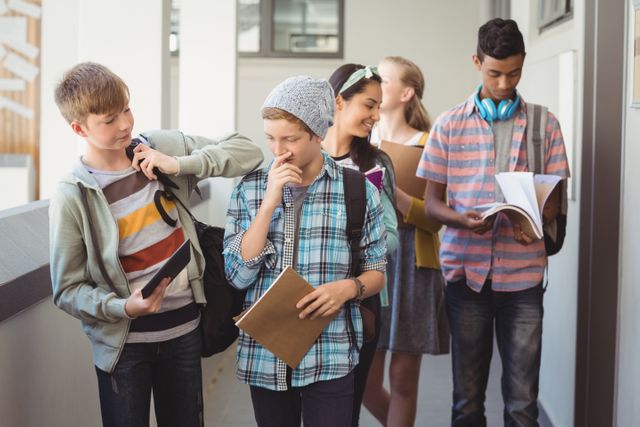 Group of diverse students walking in a school corridor, carrying backpacks and books. They appear to be engaged in conversation and studying. This image can be used for educational content, school promotions, youth programs, and articles about student life and education.
