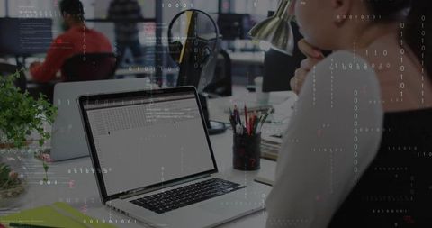 Developer analyzing code on laptop in modern office environment