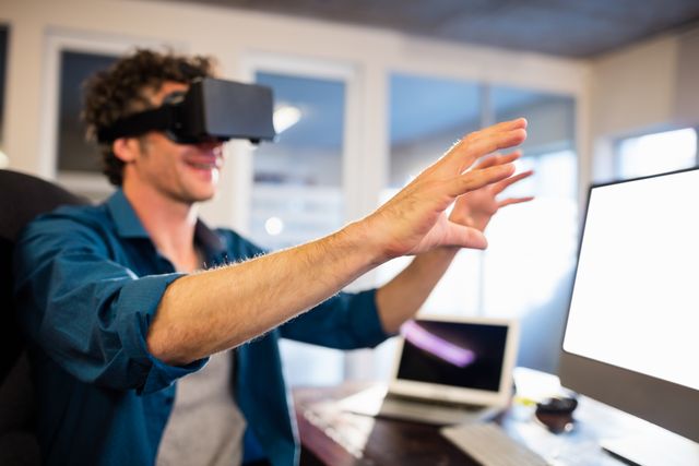 Businessman wearing VR headset in office, interacting with virtual environment. Ideal for illustrating modern technology in business, innovation in the workplace, and the future of digital interaction. Suitable for articles, blogs, and presentations on virtual reality, tech advancements, and professional environments.