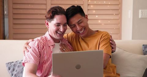 Happy Diverse Male Couple Bonding Over Technology at Home