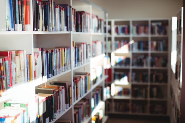 Bookshelves filled with a variety of books in a school library. Ideal for use in educational content, articles about reading and literature, or resources for students and teachers. Perfect for illustrating concepts of learning, knowledge, and academic environments.