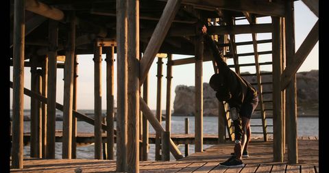 Fit young man stretching on beachfront pier