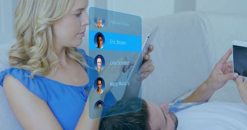 Couple using tablet displaying holographic contact list highlighting eric brown on sofa
