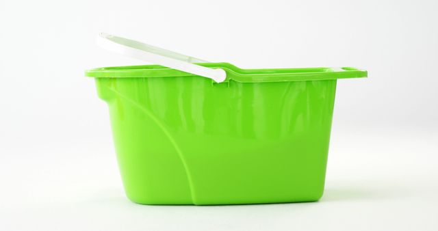 A green plastic yogurt container with a white spoon is placed against a white background, with copy space. Its bright color stands out, making it ideal for topics related to food packaging or dairy products.