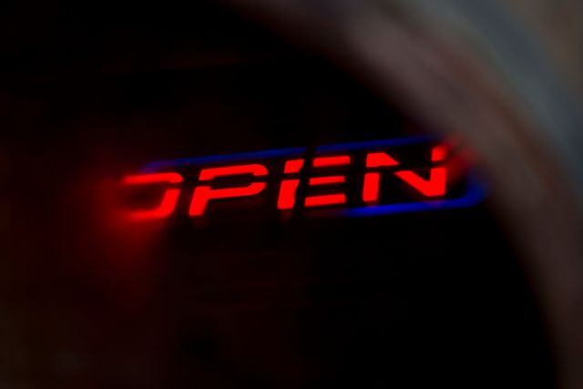 Red neon open sign glowing through a blurry window, giving an atmospheric and warm invitation to a storefront. Perfect for adding a welcoming and inviting feel to business-related materials, websites, nighttime economy features, and inspirational designs highlighting businesses.