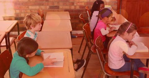 Sunlit elementary students reading at wooden desks with warm lensflare and brick backdrop