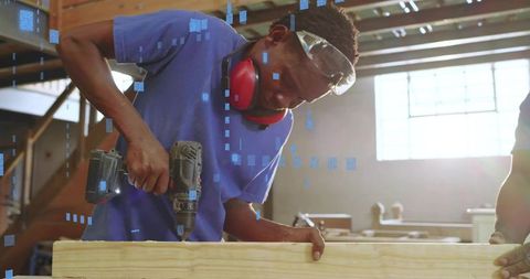Carpenter Drilling Beam with Cordless Drill Wearing Safety Goggles and Ear Protection
