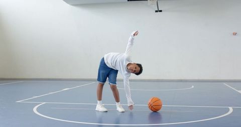 Youth Stretching and Reaching for Basketball in Indoor Court
