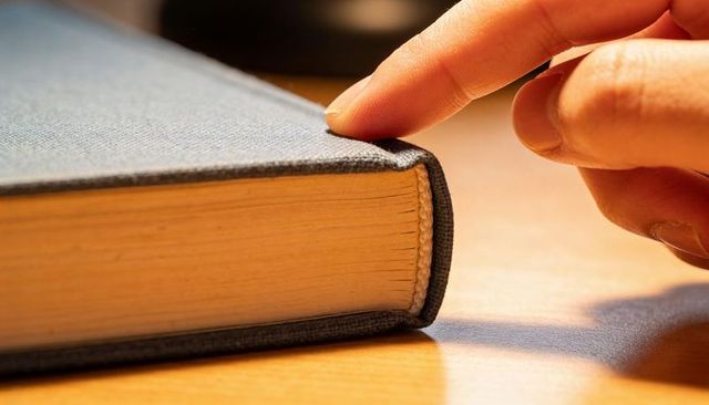 Finger Peeling Back Cloth Cover on Hardcover Book Closeup Showing Aged Pages and Binding
