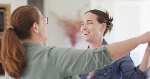 Happy Lesbian Couple Dancing Together in Sunlit Kitchen